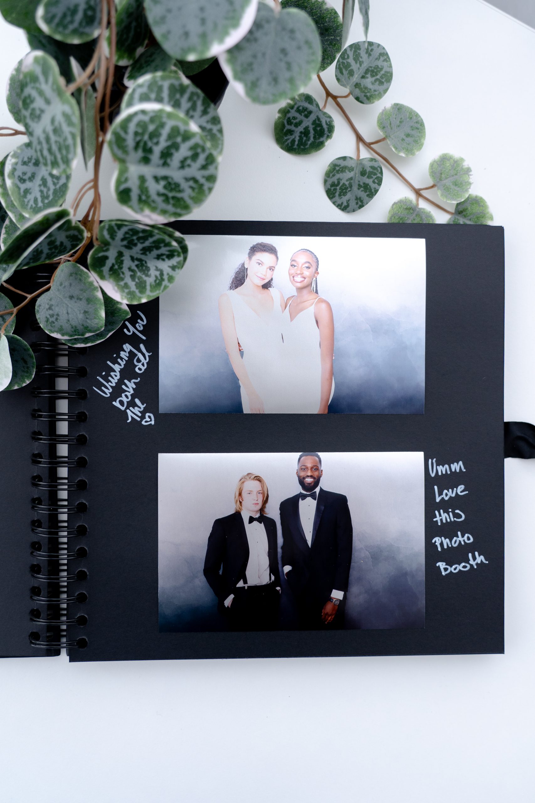 An open leather-bound guestbook filled with photo booth strips and handwritten notes from guests